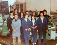 Grupo de alumnos y alumnas de la 33 Promocin de la Escuela de Aprendices de RENFE en Len, de fecha de 18 de septiembre de 19778, primera promocin de la escuela en la que ingresaron mujeres, posando en el interior de los talleres de la Escuela. En primer trmino, a la izquierda con bata, se identifica al profesor Jos Luis Ropero, junto a l, Susana Rodrguez de Arce, y a su lado, la propia hija del profesor, Mercedes Ropero. 1978 - Len